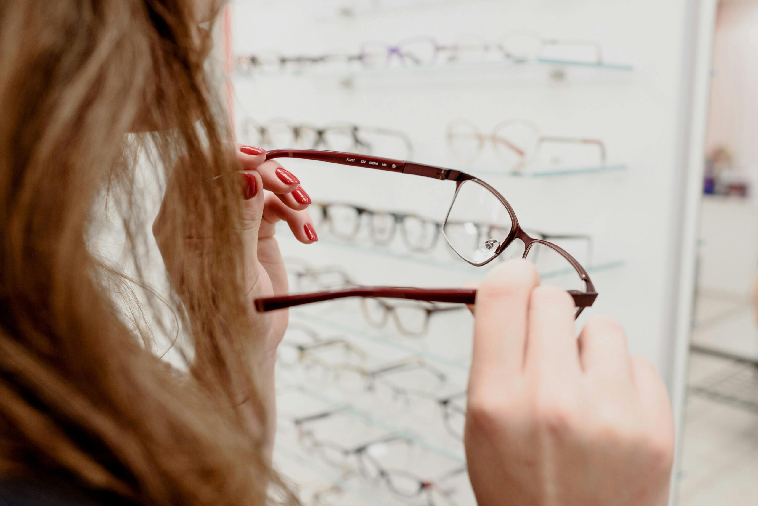 pexels-photo-5766531-5766531 A woman examines a pair of eyeglasses in an optical store, deciding on the perfect fit.